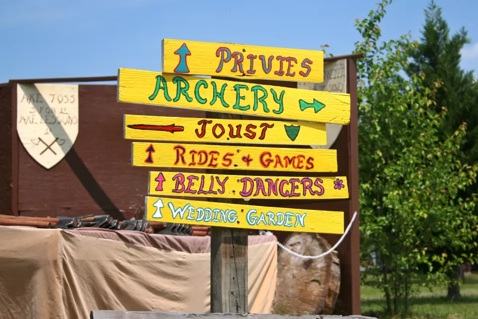 Signpost with signs for archery, jousting, privies, etc at Renaissance faire